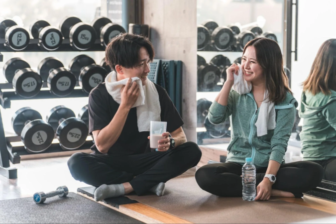 ジムでのトレーニング後に休憩している男女の様子