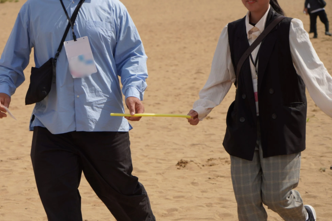 砂地で黄色い棒を持つ二人