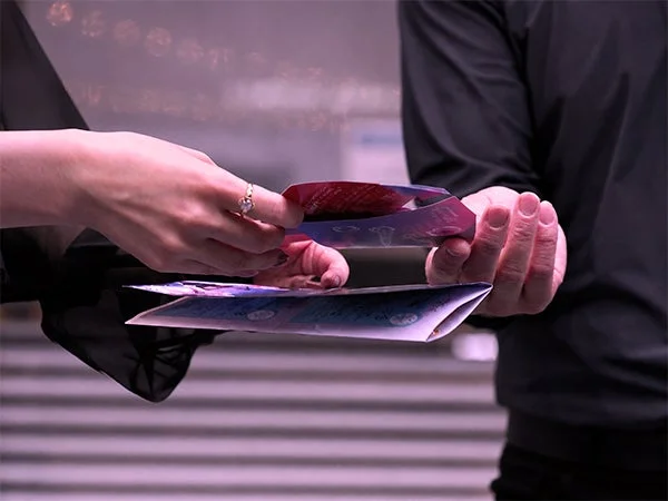 二人の人物がカラフルなパンフレットやカードをやり取りしているクローズアップ画像