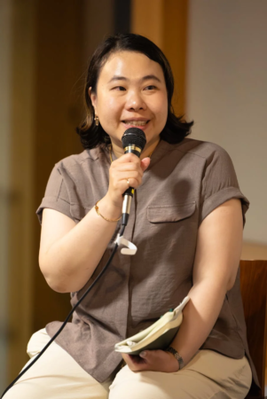マイクを持って笑顔で話す女性