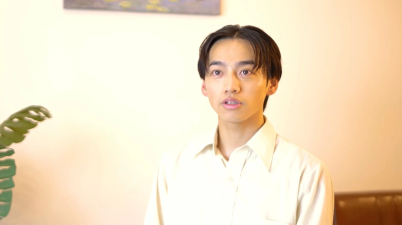 白いシャツを着た若いアジア人男性がカメラをまっすぐ見つめている上半身のポートレート