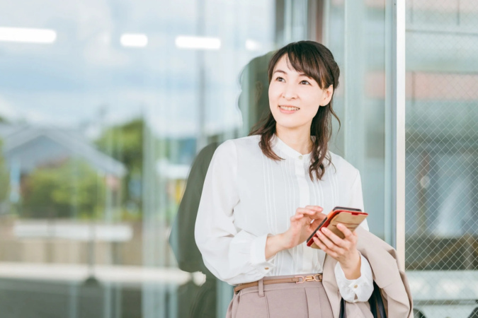 スマートフォンを操作しながら笑顔の女性のポートレート