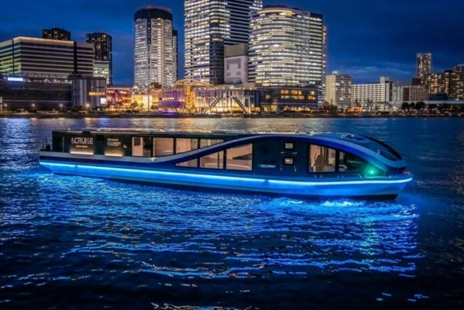 夜の都市のビル群を背景に、青いライトで幻想的にライトアップされたモダンなクルーズ船