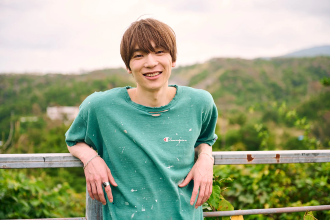 笑顔の若い男性が手すりに寄りかかっている